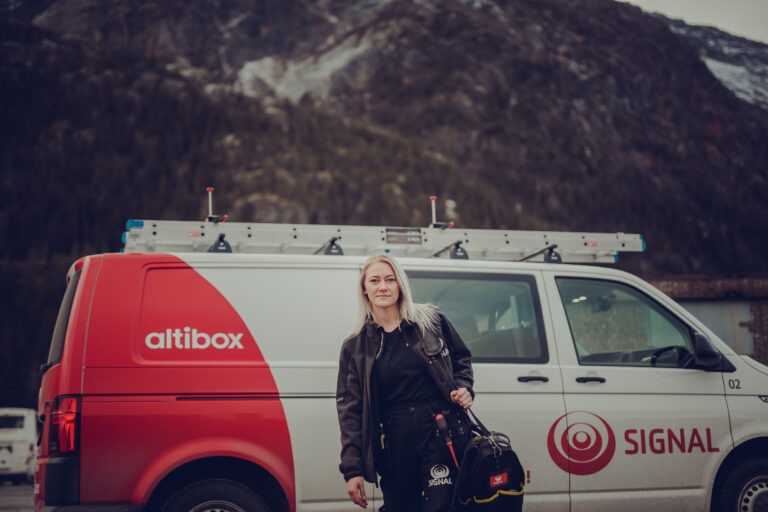 Lærlingen Betty fra Signal Bredbånd er på oppdrag med Signals bil i bakgrunnen