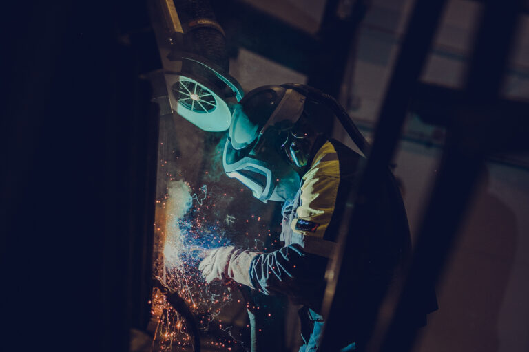 Sveiser bruker sveiseapparat på metall så gnistene spruter